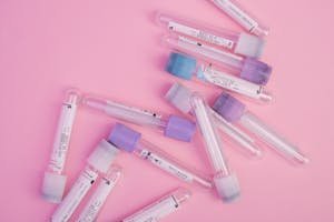 Multiple test tubes with colorful caps scattered on a pink surface, ideal for science themes.