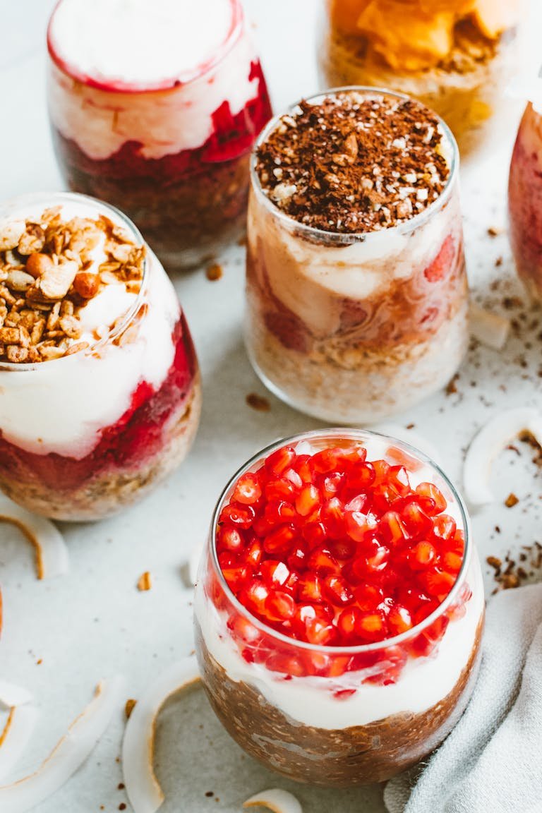 Tempting yogurt parfaits with layers of fresh fruits and creamy yoghurt in clear glasses.